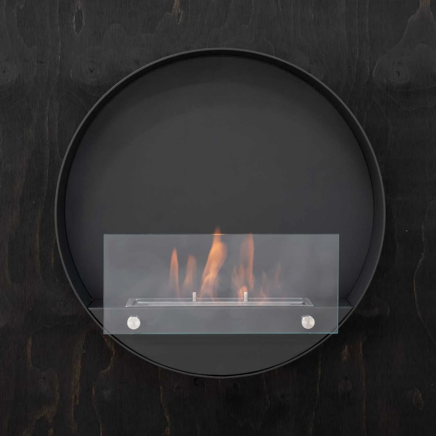 Delaware S black round bio fireplace mounted on a dark wood-textured wall, lit with a realistic flame