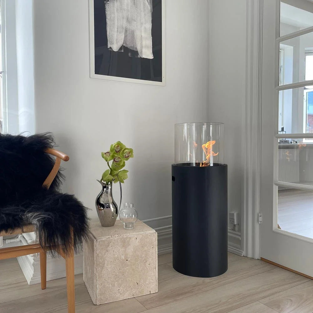 ScandiFlames outdoor black bioethanol fireplace lit in a modern living room beside a fur throw and orchid